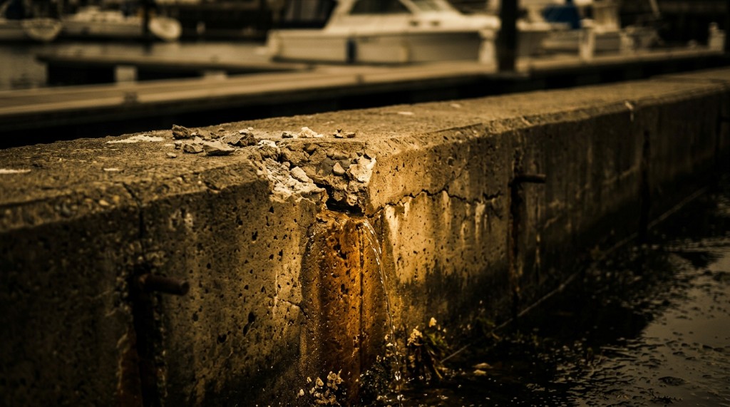 Water streaming from a vertical fissure in a deteriorated concrete seawall